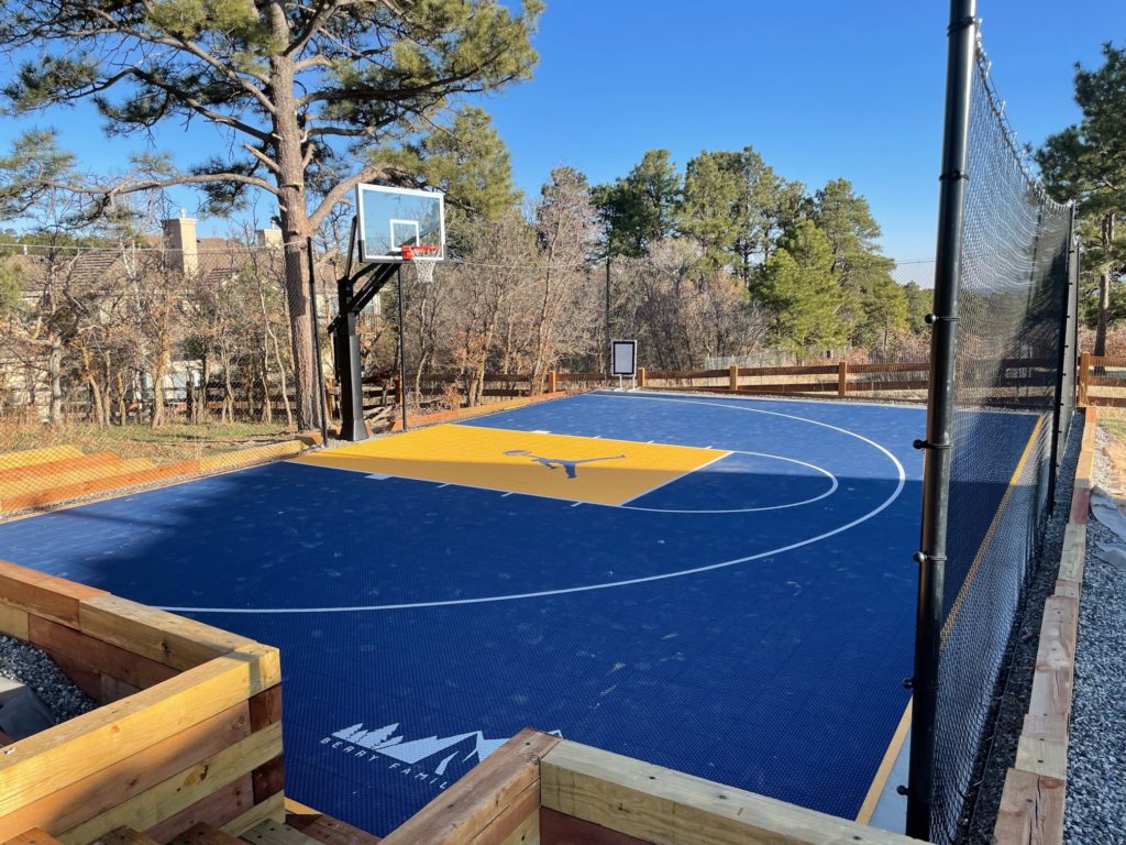 Residential basketball court with basketball containment netting.