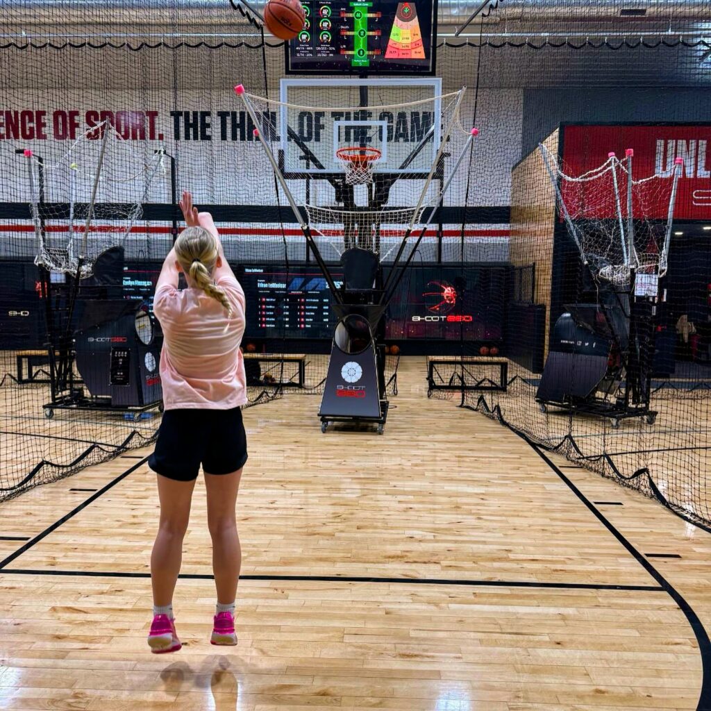 A custom gym divider net separating basketball courts inside a large gymnasium.